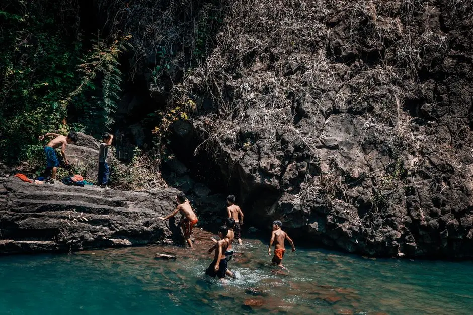 Keluarga bermain air di kolam alami Air Terjun Bukit Tiga